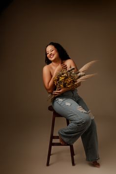 a woman is sitting on a stool with feathers in her lap and smiling at the camera