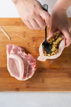 a person cutting meat on top of a wooden cutting board