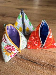 three small zippered pouches sitting on top of a wooden table