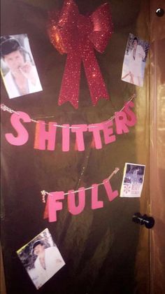 a door decorated with pictures and red ribbon that says, shitter full on it