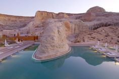 an outdoor swimming pool in the middle of a desert area with large rocks surrounding it