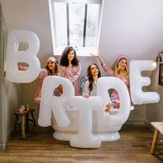 four women standing behind giant letters that spell out the word b is for b is for b is for b is for b