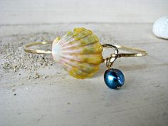 "The Sunrise Shell is prized for its rarity. It is found only in the Hawaiian Islands, and rarely found on the beach. Most of them are found by divers, deep in the ocean. My Sunrise Shells are found by my husband and a close family friend. Our Sunrise Shell creations are a true LABOR OF LOVE. From my husband diving to extreme depths to unearth these beauties beneath layers of sand, to the labor-intensive processing of the shell (to remove any natural calcification of the shell), to the final des Ocean-inspired Shell Oyster Bracelet Jewelry, Ocean-inspired Shell Oyster Bracelet, Unique Beach Bangle Jewelry, Ocean-inspired Bangle Jewelry For Gifts, Ocean-inspired Shell Bracelet Jewelry, Sunrise Shell, Seashell Bracelet, Black Freshwater Pearls, Pearl Bangle