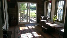 the sun shines through two windows into a living room with wood flooring and furniture