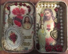 an open tin box with rosarys and pictures on it