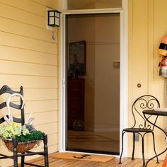 the front door is open and there are two chairs on the porch