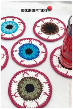 crocheted coasters with different colors and designs on them, one has a red cup in the middle