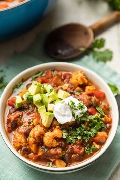 a white bowl filled with cauliflower chili and avocado