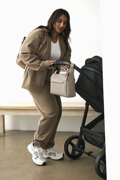 a woman is pushing a stroller and looking at the contents in her handbag