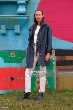 a woman standing in front of a colorful wall with a blue coat over her shoulders