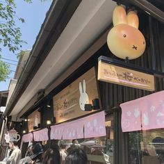 people are walking past a store front with bunnies hanging from the side of it