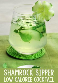 a glass filled with water and cucumber on top of a green table cloth