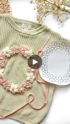 a knitted sweater with crochet work on it next to a paper plate