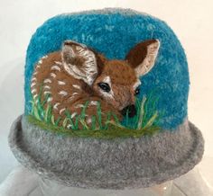 A felted alpaca hat highlighted by  popular FAWNS The needle felt art can highlight the front, side or back, however you want to wear it. You can wear it with a curled brim or a flat brim. THE HATS ARE HAND KNIT FROM 1 STRAND OF BABY ALPACA FOR SOFTNESS AND ONE STRAND OF WOOL FOR SHAPE. They are then felted and finally needle felted MY FELTED HATS ARE ADJUSTABLE  AND FIT--20"--23.5' (SMALL-LARGE WIDTH). IF THE HAT FEELS A LITTLE LOOSE, YOU CAN TIGHTEN IT BY PULLING ON THE INSIDE BUTTON AND STRIN Needle Felt Art, Felted Alpaca, Handmade Felt Hats, Alpaca Hat, Felted Hats, Fawn Deer, Felted Hat, Deer Art, Bowler Hat