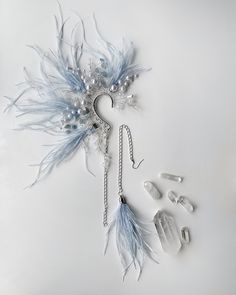 an assortment of jewelry is displayed on a white surface with beads and feathers attached to it