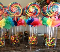 there are many lollipops in glass vases on the table with candy