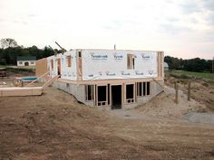 a house under construction in the middle of an open field with lots of dirt around it