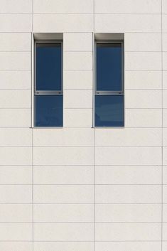 two windows on the side of a white building