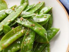 a white plate topped with green beans covered in salt and seasoning next to a blue towel