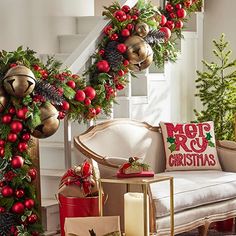 christmas decorations and presents are arranged on the floor in front of a stair case, decorated with greenery