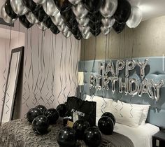 a bedroom decorated with black and silver balloons for a happy birthday party at the hotel