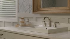 a bathroom sink with two faucets and a mirror above it on the wall