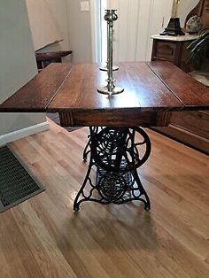 an antique sewing machine table in the middle of a room with hardwood floors and white walls