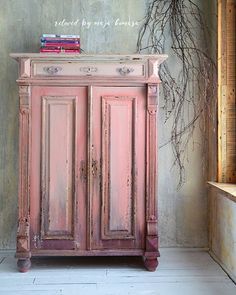 an old pink cabinet with books on top