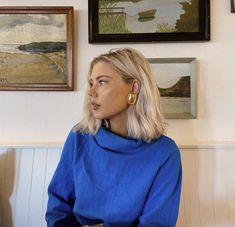 a woman sitting on a bench in front of some pictures and paintings hanging on the wall