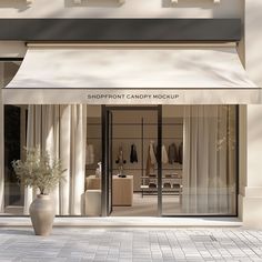 a store front with an awning over the entrance to it and two vases filled with flowers