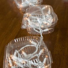 three clear plastic containers with white lights on them sitting on a wooden table next to each other