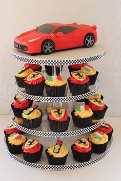 cupcakes are stacked on top of each other in front of a red sports car