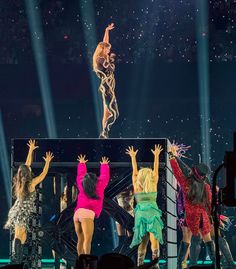 the dancers are performing on stage with their arms in the air