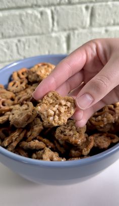 a hand reaching for some cereal in a blue bowl on top of a white table