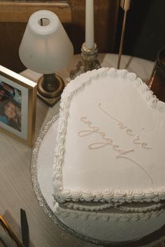 a heart shaped cake sitting on top of a table next to a candle and pictures