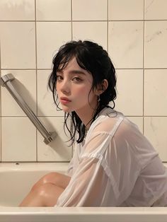 a woman sitting in a bathtub next to a tiled wall