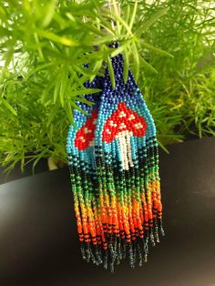 the beaded necklace is colorful and has mushrooms on it, as well as green grass