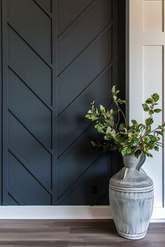 Elegant dark blue paneled wall with a classic white door on the right and a large ceramic vase holding greenery on a wooden floor. Wood Slat Dining Room, Dining Accent Wall Ideas, Accent Wall Wood Trim, Wood Trim Accent Wall Bedroom, Box Trim On Wall, Entry Accent Wall, Wood Trim Interior, Trim Accent Wall Ideas, Entryway Accent Wall Ideas