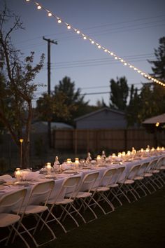 a long table is set up with candles and place settings for an outdoor dinner party