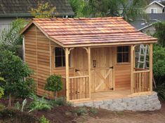 a small wooden shed sitting in the middle of a yard with trees and bushes around it