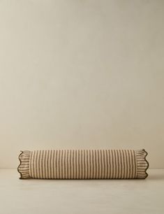 a striped pillow sitting on top of a white table next to a brown and white wall