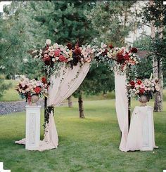 an outdoor ceremony setup with flowers and drapes