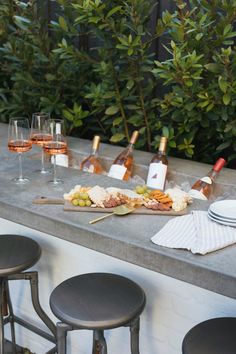 a long table with wine glasses and plates on it next to some bottles of wine