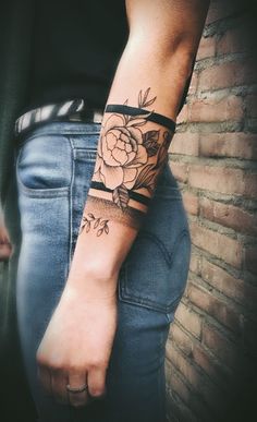 a woman's arm with a rose tattoo on the wrist and black ribbon around it