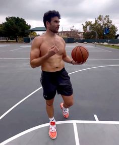 a shirtless man holding a basketball in his right hand while standing on a basketball court