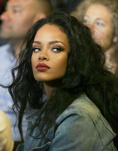 a close up of a person with long hair wearing a jean jacket and red lipstick