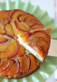 a piece of cake with peaches on it is sitting on a green paper plate