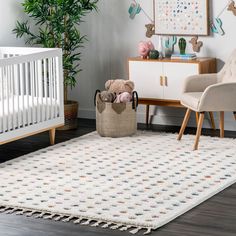 a baby's room with a white crib, chair and rug in it