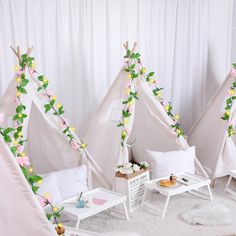 three teepees are decorated with flowers and greenery