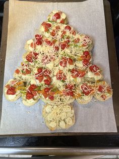 a christmas tree shaped pizza sitting on top of a cookie sheet covered in cheese and toppings